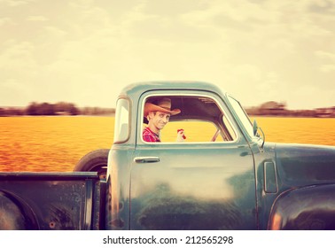 a handsome man with a cowboy hat on driving a truck past a field full of yellow flowers toned with a retro vintage instagram filter effect  - Shutterstock ID 212565298