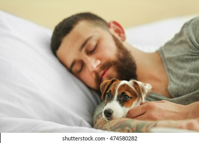 Beau homme avec un chien mignon dormant dans son lit