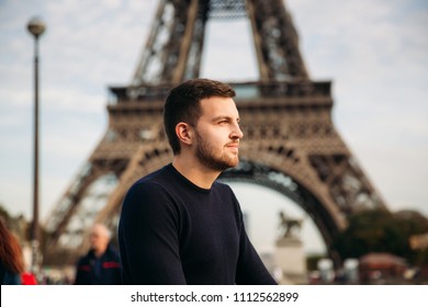 Handsome man in dark pullover is standing on the bridge background of the Eiffel Tower