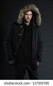 Handsome Man Dark Winter Fashion. Studio Shot. Wearing Black Hood Jacket And Gloves.