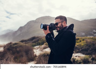 Handsome Man With Digital Camera Outdoors. Young Male Photographer Photographing In Nature On Winter Day.