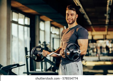 Handsome man doing biceps lifting in a gym