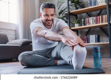 Handsome man doing hamstring stretch exercise at home. - Powered by Shutterstock