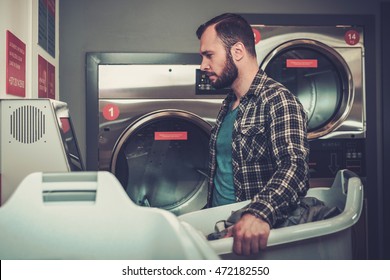 Handsome Man Doing Laundry At Laundromat Shop