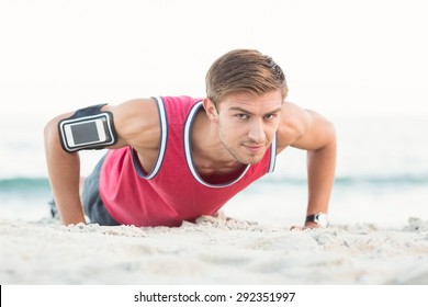 Handsome man doing push ups at the beach