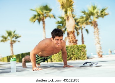 Handsome man doing push ups on the beach.