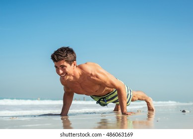 Handsome man doing push ups on the beach.