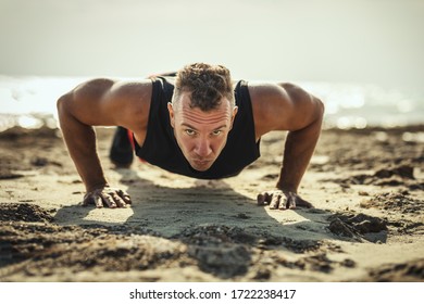 A handsome man is doing push-up exercise at the sea beach in summer sunny day.