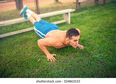 handsome man doing push-ups in park, bodybuilding and training. Fitness concept with shirtless man outdoors, doing exercises