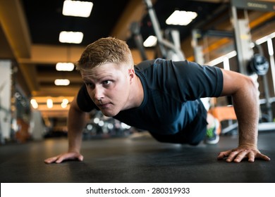Handsome man doing push-ups in sports club