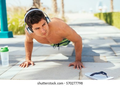 Handsome man doing some push ups on the beach.