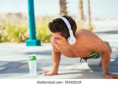 Handsome man doing some push ups on the beach.