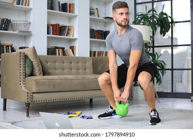 Handsome man doing sport exercise with kettlebell at home. Concept of healthy life. - Shutterstock ID 1797894910