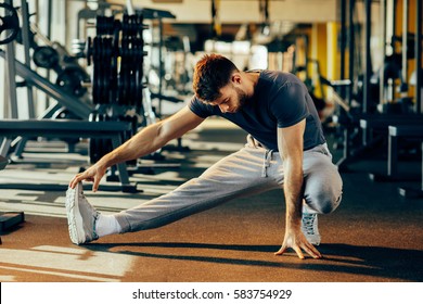 Handsome Man Doing Warm Up In The Gym And Stretch Legs