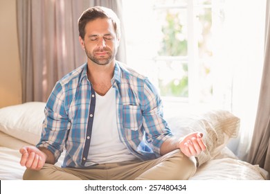 Handsome man doing yoga on his bed at home in bedroom