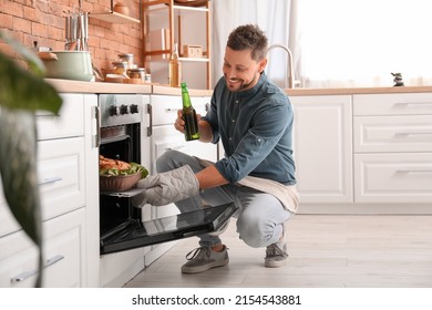 Handsome man drinking beer while cooking in kitchen - Powered by Shutterstock