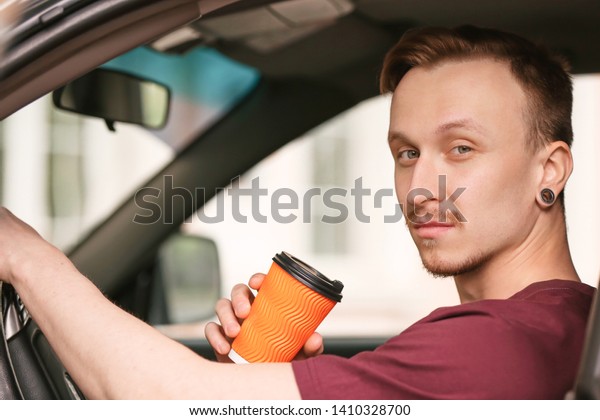 Handsome man drinking coffee\
in car
