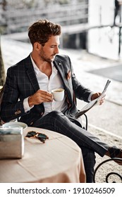 Handsome man drinking coffee and reading newspaper in cafe - Shutterstock ID 1910246509