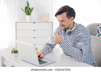 Handsome man drinking coffee while working on laptop at home