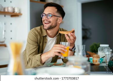 Handsome man drinking juice in kitchen. Young man eating breakfast at hoe. - Powered by Shutterstock