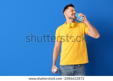 Handsome man drinking soda on color background