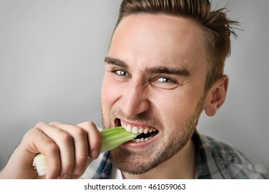 Handsome Man Eating Celery On Grey Background