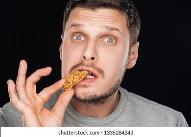 Handsome Man Eating Chicken Nugget While Looking At Camera Isolated On Black