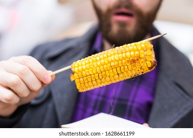 Handsome Man Eating A Delicious Corn Cob On The Street