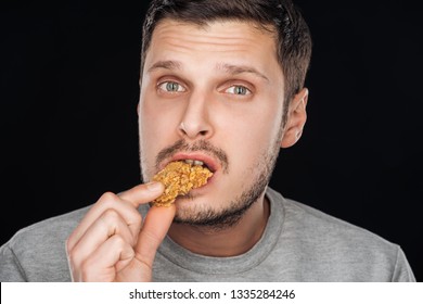 Handsome Man Eating Tasty Chicken Nugget While Looking At Camera Isolated On Black