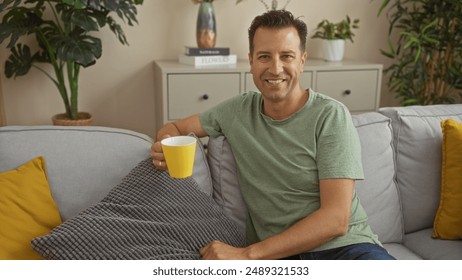 Handsome man enjoying coffee in a cozy living room, smiling while holding a yellow mug, surrounded by indoor plants and comfortable decor. - Powered by Shutterstock