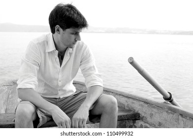 Handsome man expressing sadness sitting on a boat black and white