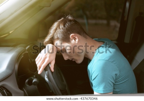 Handsome man falling asleep in\
car