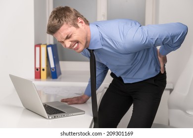 handsome man feeling pain in back. Businessman suffering from back pain at office 