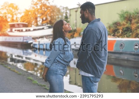 A handsome man flirting with  a beautiful smiling woman as they walk along the channel  quay