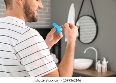 Handsome Man Flossing Teeth In Bathroom