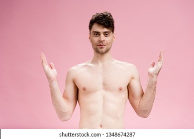 handsome man gesturing and looking at camera on pink