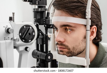 Handsome man getting an eye exam at ophthalmology clinic. Checking retina of a male eye close-up