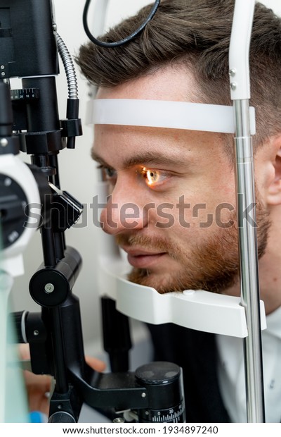 Handsome man is getting an eye\
exam at ophthalmology clinic. Male is checking retina.\
Close-up