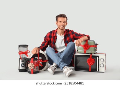 Handsome man with gift appliances sitting on grey background - Powered by Shutterstock