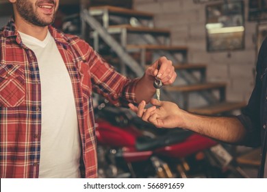 Handsome Man Is Giving A Key To The Owner Of The Motorcycle While Both Are Standing In The Repair Shop