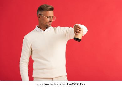 Handsome Man In Glasses Holding Paper Cup Upside Down Isolated On Red 