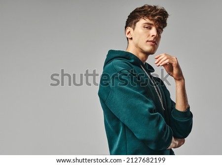 Handsome man in green hoodie isolated on gray background