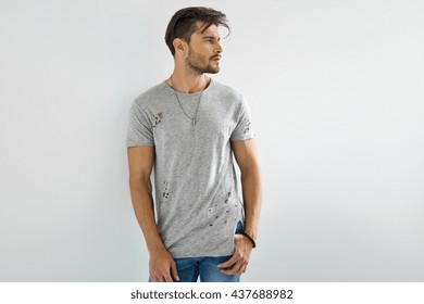 Handsome man in grey t-shirt posing on white background