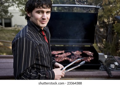 A Handsome Man Grilling Steak On The Barbeque