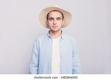 Handsome man in hat looking at camera, grey background, portrait