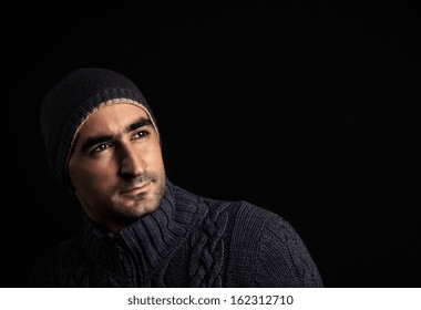 Handsome man in hat and pullover looking up