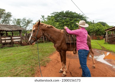 handsome man in hat saddling the horse on the farm - Powered by Shutterstock