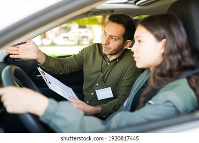 Handsome Man In His 30s And Beautiful Teen Girl Sitting Inside A Car For A Driving Exam. Male Instructor Giving Directions To An Adolescent Girl During Her Lesson