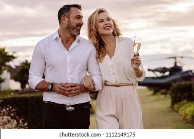 Handsome man with his beautiful girlfriend walking together outdoors. Beautiful couple walking outdoors with a helicopter at the back. - Shutterstock ID 1112149175