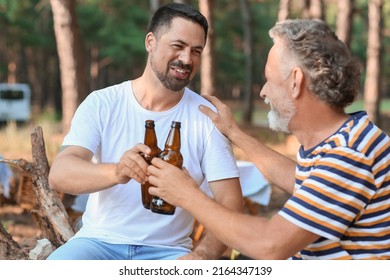 Handsome man with his father drinking beer in forest